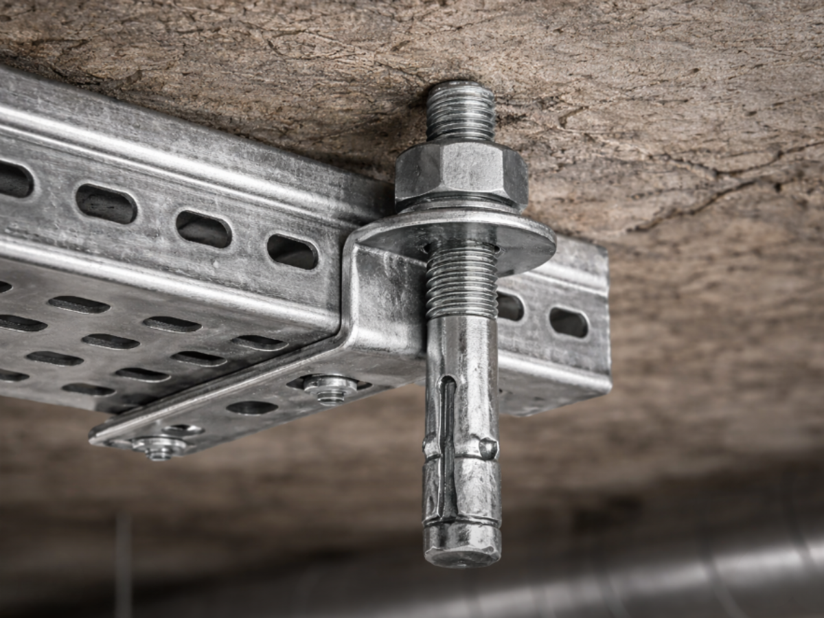 Structural anchor fixing supporting a metal bracket and threaded rod beneath a concrete ceiling for mechanical and electrical service installation.
